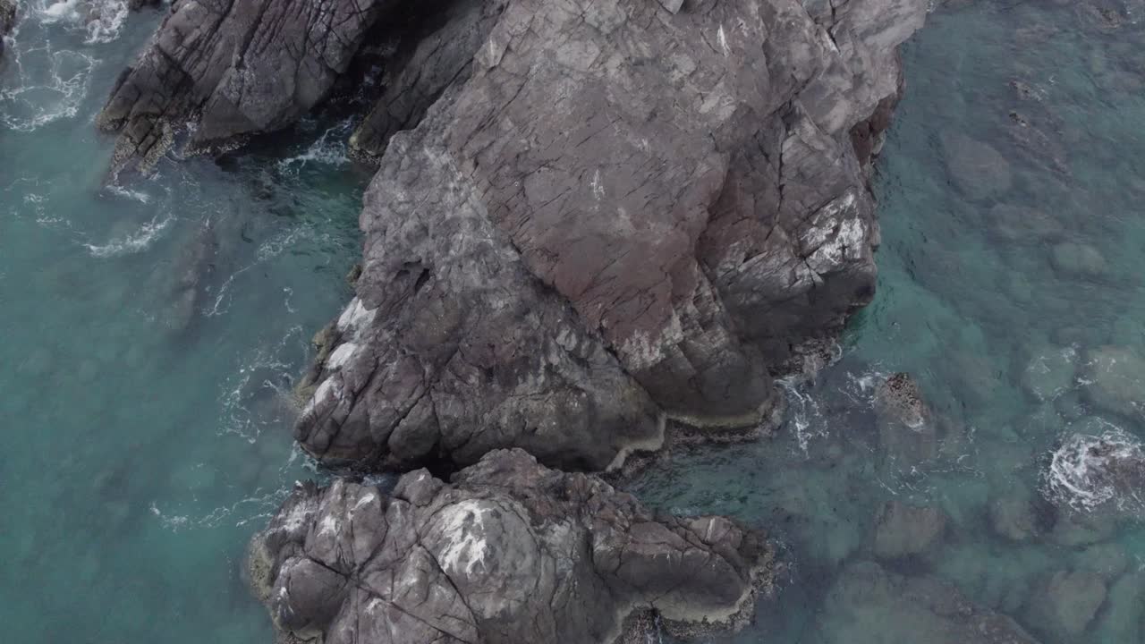 Inclinazione verso il basso con vista drone di una grande roccia a lato dell'oceano in una mattina nuvolosa a Cabo Pulmo, Messico.