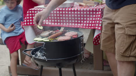 zbliżenie nierozpoznawalnego mężczyzny gotującego i kładącego warzywa na grillu podczas rodzinnego pikniku