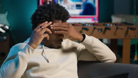black person having health problems suffering from headache and nausea, sitting in the living room and struggling to work on tasks. remote worker suffering from illness at home. camera a.