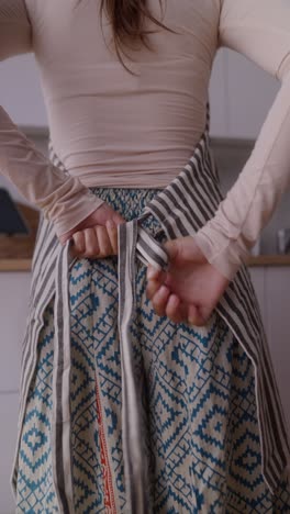 woman tying an apron in a kitchen