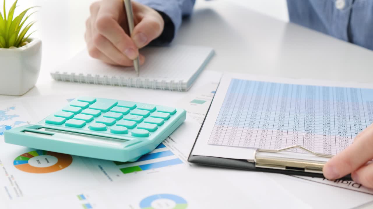 las manos de un contador trabajan en una calculadora y preparan un informe financiero.