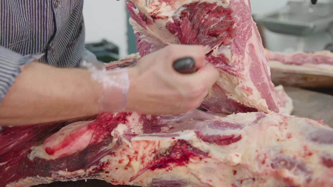 A Butcher cutting beef with a butcher's knife and meat hook