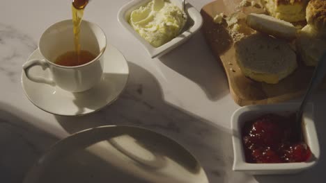 studio shot of person with traditional british afternoon tea with scones cream and jam 4