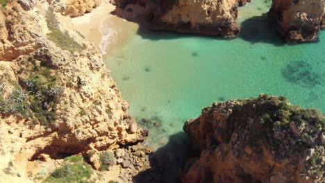 Fly-over-limestone-cliffs,-rock-formations-of-different-shapes-and-sizes-against-blue-ocean-water