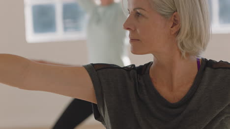 yoga class portrait beautiful elderly woman exercising healthy lifestyle practicing warrior pose enjoying group fitness workout in studio