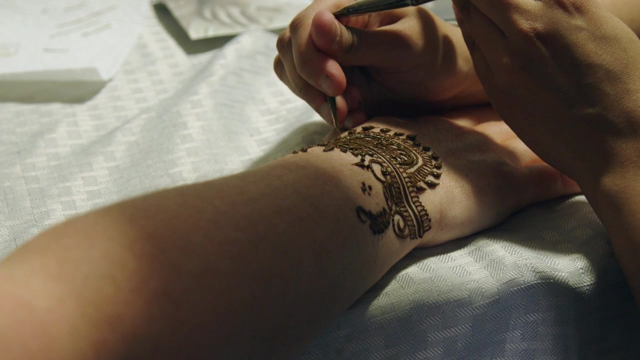 Design geometrico tradizionale indiano applicato sulla mano di una donna con l'henné