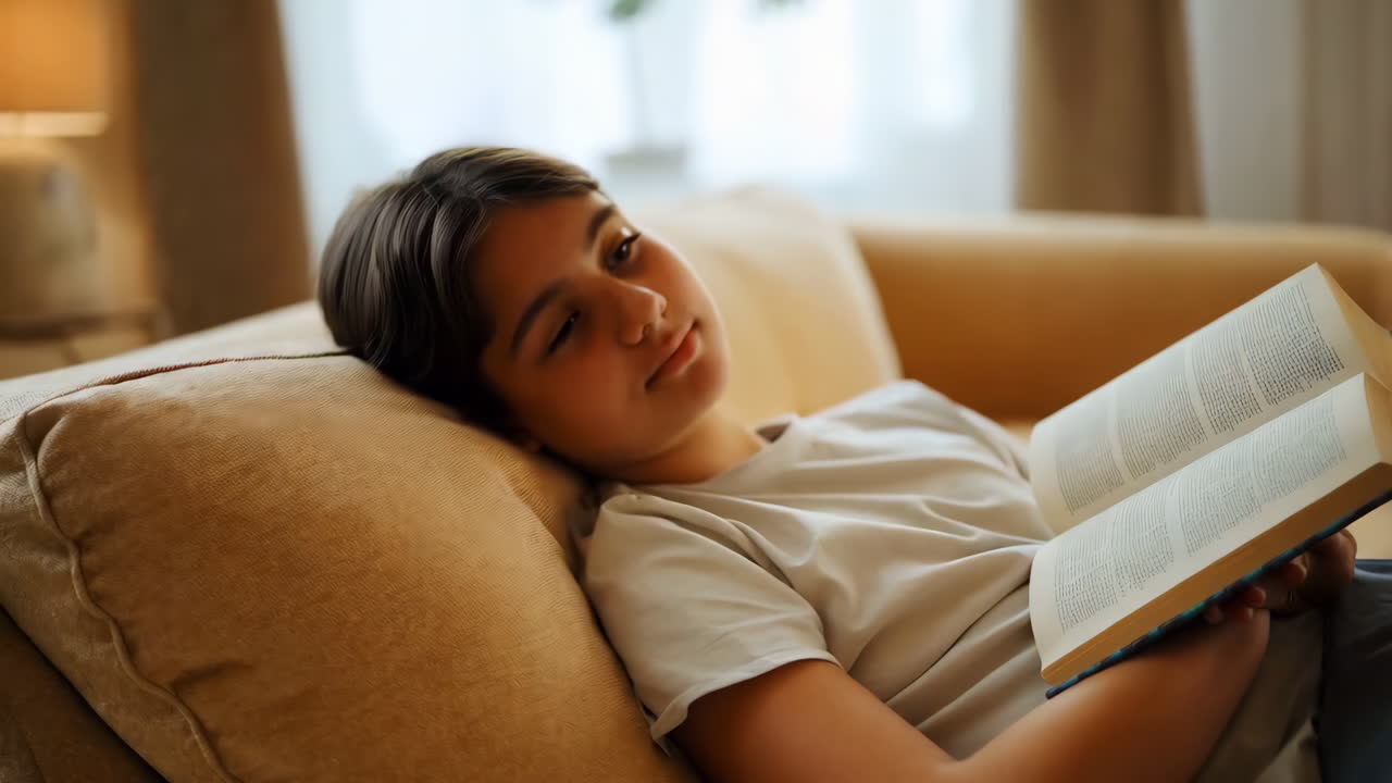 Young person napping on a couch with a book