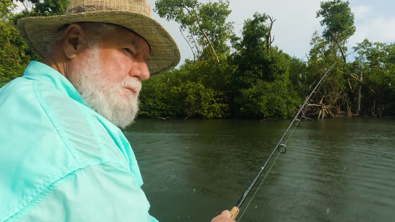 viejo pescador atrapando peces con caña de pescar, día lluvioso, de mano