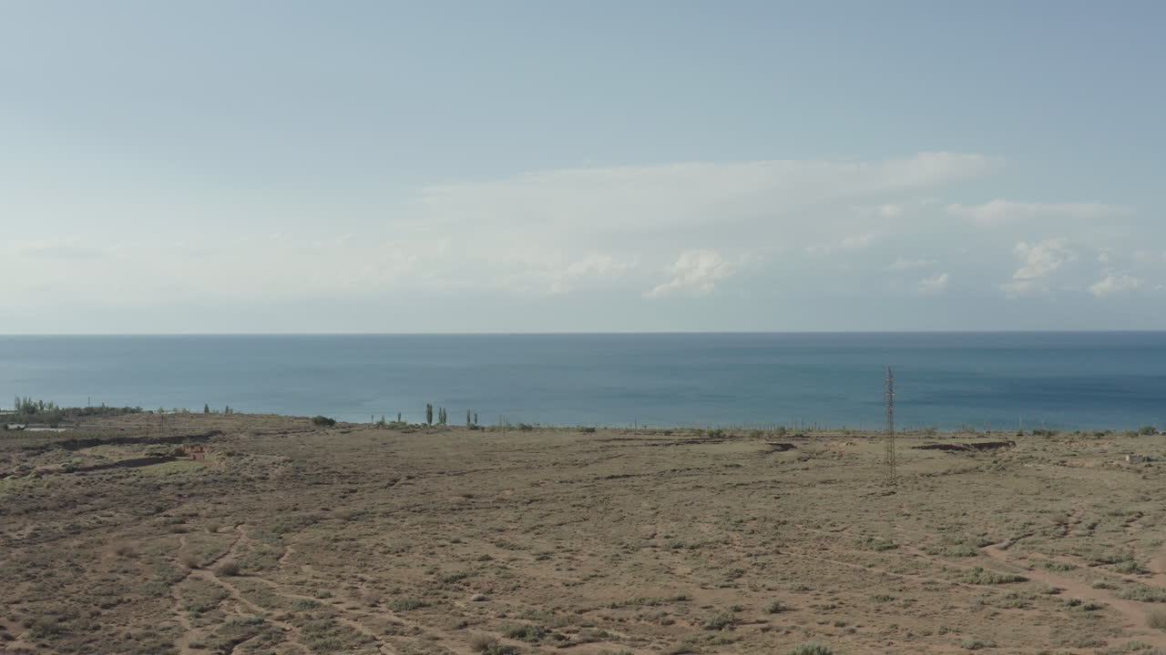 Barren land leading to the calm blue waters of the lake in kyrgyzstan, aerial view