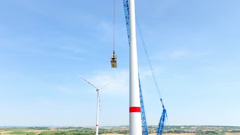 wind turbine nacelle lifted by crawler crane for installation at wind power plant