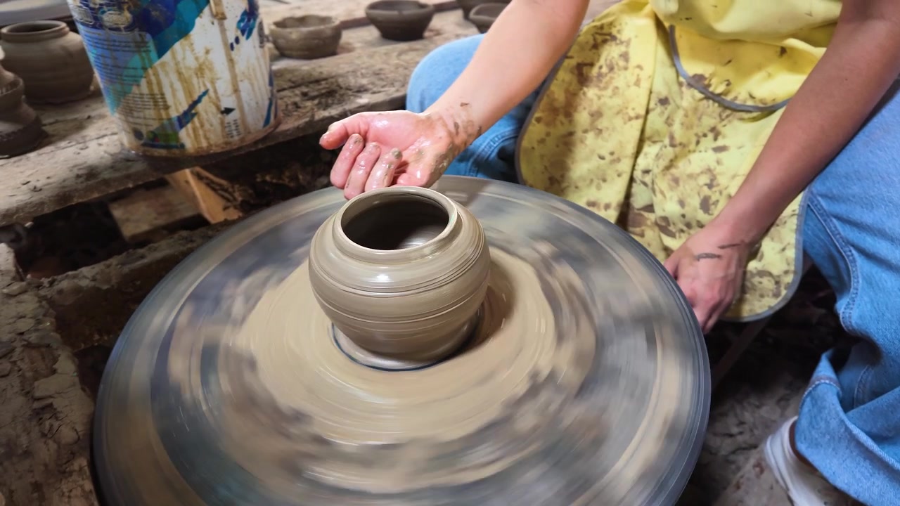 Primo piano delle mani di un vasaio che modellano un vaso di ceramica su un tornio tradizionale