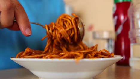 young alone man eating pasta