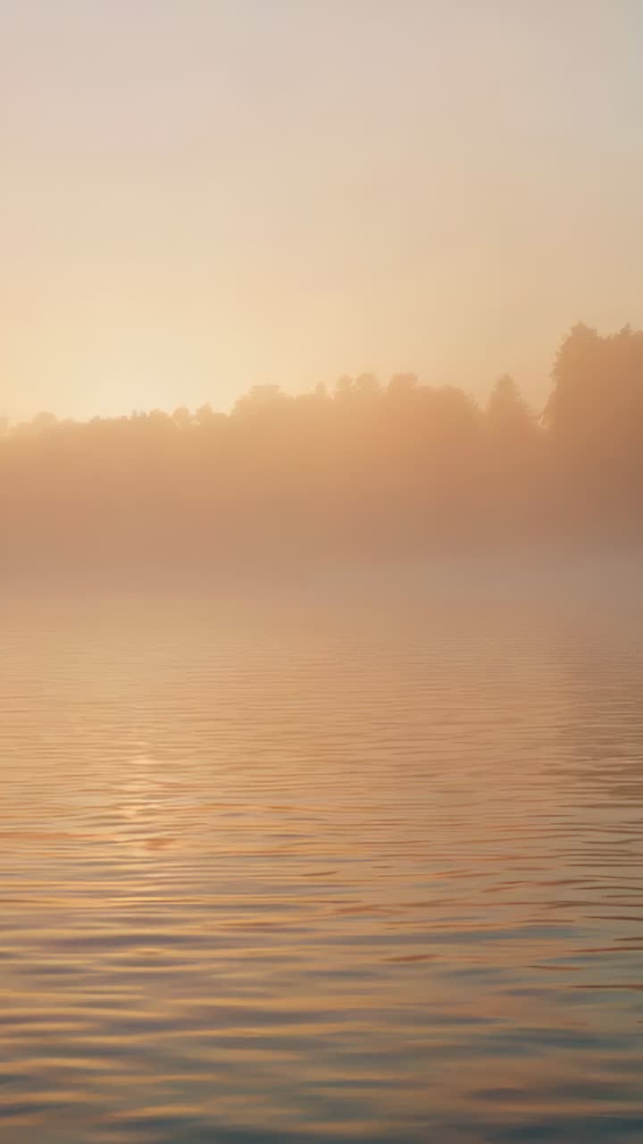 Vertical video: Emerging sun brightening lake sky at sunrise, mist thinning and reflection growing