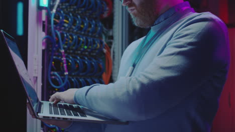 it professional working on a laptop in a server room