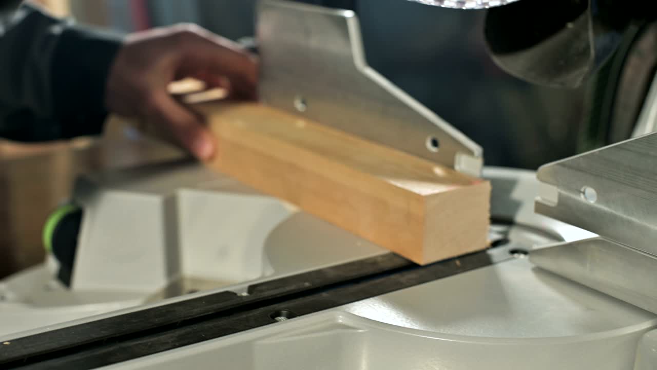 un joven carpintero instala una pieza de madera en una sierra circular