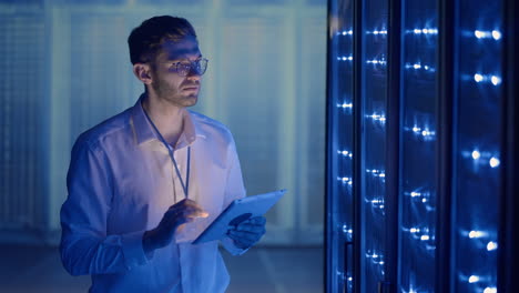 técnico en la sala de servidores digitales del centro de datos controlando el trabajo de los gabinetes de servidores de rack con una tableta. ingeniero profesional de servidores en el trabajo.