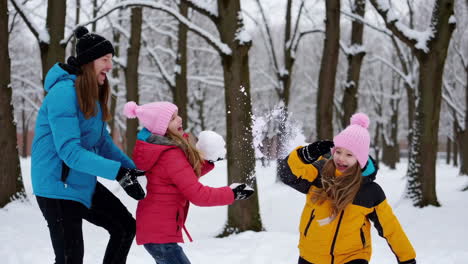 family and kids having a joyful snowball fight in a winter park