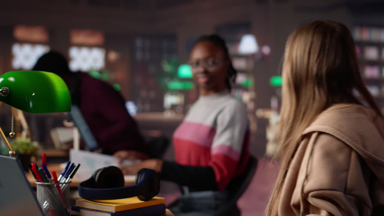 Vertical video girl shares a high five with her african american colleague at the library