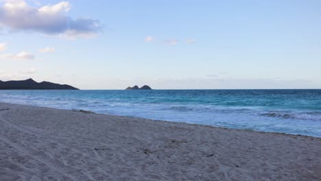 Kleine-Wellen-Brechen-An-Einem-Ruhigen-Sandstrand-Mit-Blauem-Himmel-Und-Geschwollenen-Weißen-Wolken