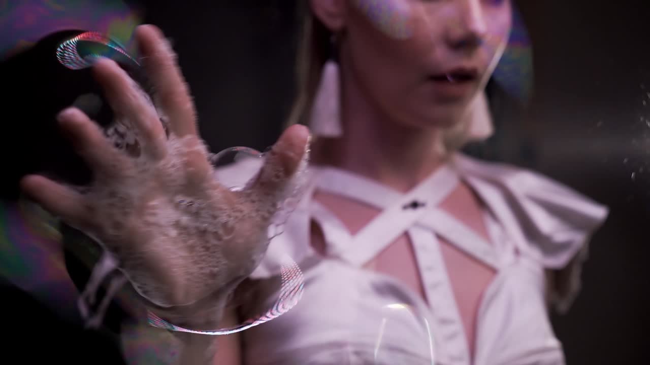 de cerca: chica hace trucos con burbujas de jabón. juega con sus manos mojadas en la pantalla de jabón
