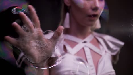 close up: girl does tricks with soap bubbles. she plays by her wet hands on the soap screen