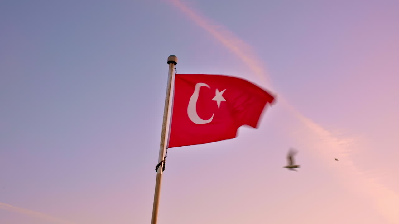 İstanbul'da dalgalanan Türk bayrağı. Gün batımı gökyüzü ve arka planda uçan kuşlar