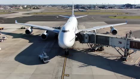 a large passenger aircraft is at the gate, getting ready for departure. ground crew members are seen assisting with the boarding process while luggage is loaded onto the plane.