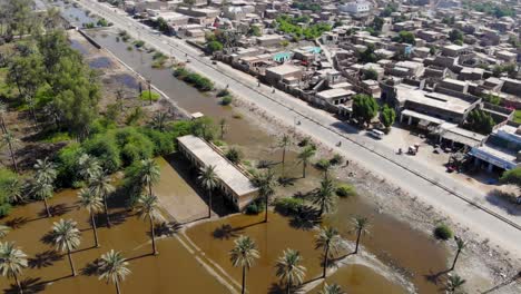 aerial view of rural farmland under water due to flooding in khairpur with tilt up, dolly back reveal of local town