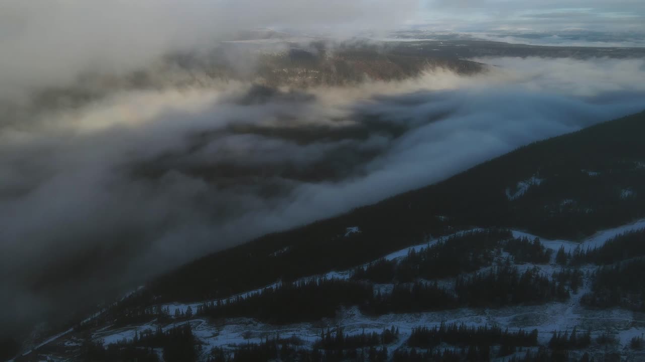 Valley covered by clouds at sunrise. Skiing slope in foreground. Drone footage, Southern Norway
