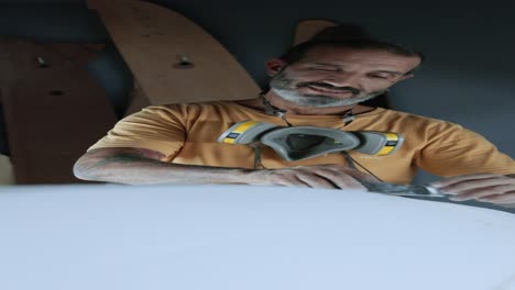 calm man shaping surfboard with instrument