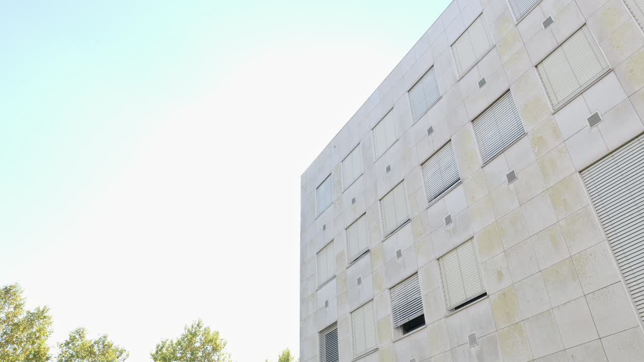 Low-angle shot of a modern university building with minimalist architecture and geometric windows