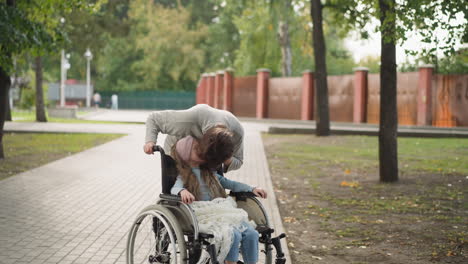 Redhead-woman-leans-to-kiss-little-girl-with-disability