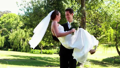 Groom-picking-up-his-pretty-new-wife-in-the-park