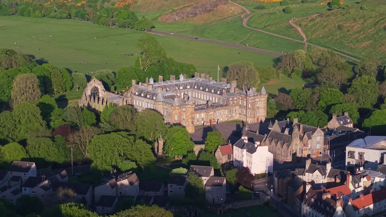 Drone orbit capturing Holyroodhouse Palace and historic Holyrood Abbey, revealing stunning architecture and surrounding greenery in Edinburgh’s royal heritage site