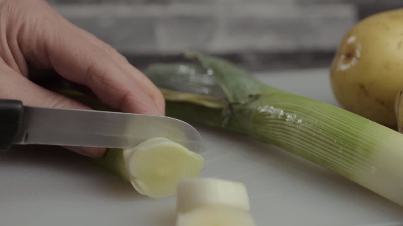 Hand slicing leek vegetable with close up shot