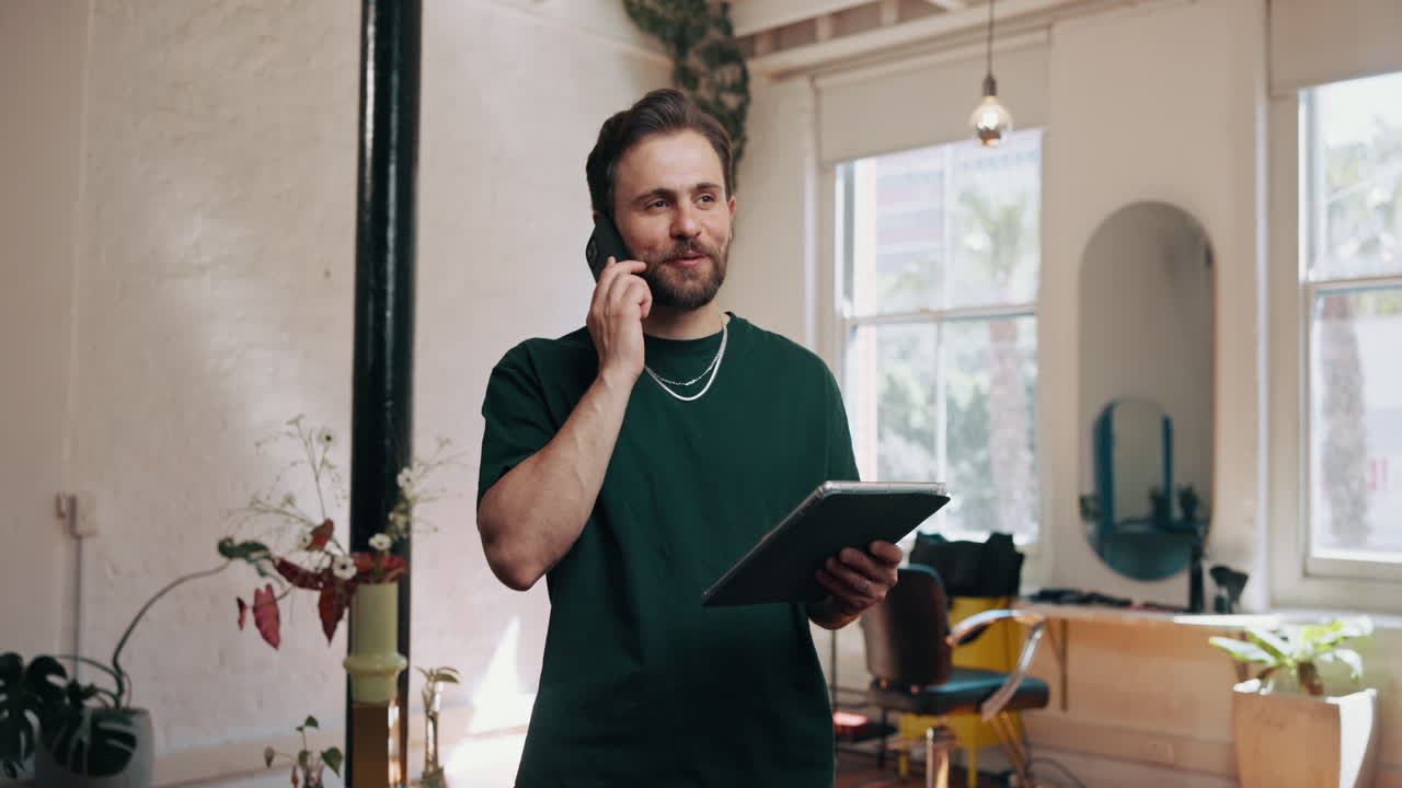 Uomo che parla al telefono e tiene un tablet in un ambiente di lavoro moderno