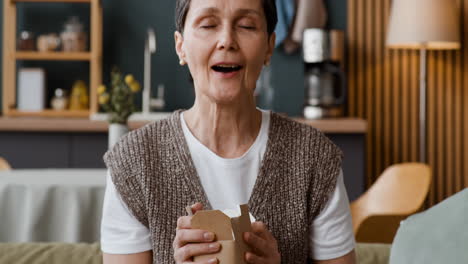 person enjoying the aroma and contents of a take-out container at home