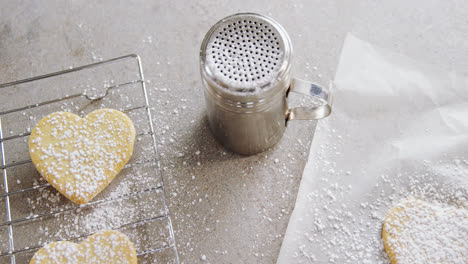 raw heart shape cookies on baking tray with flour shaker strainer, cookie cutter and wax paper 4k