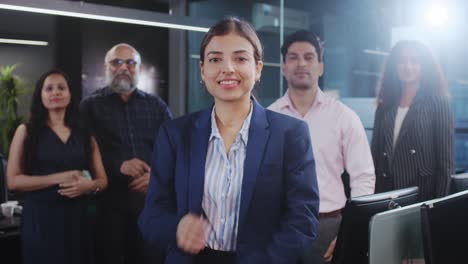 mujer corporativa india con empleados de oficina de género mixto con los brazos cruzados.