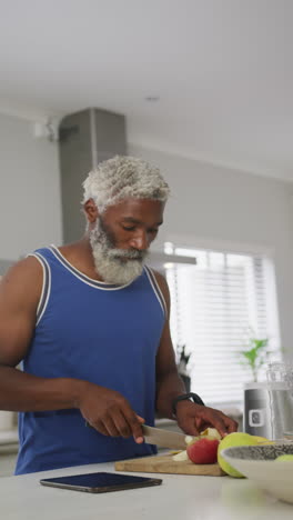 vertical video of senior african american man preparing breakfast at home