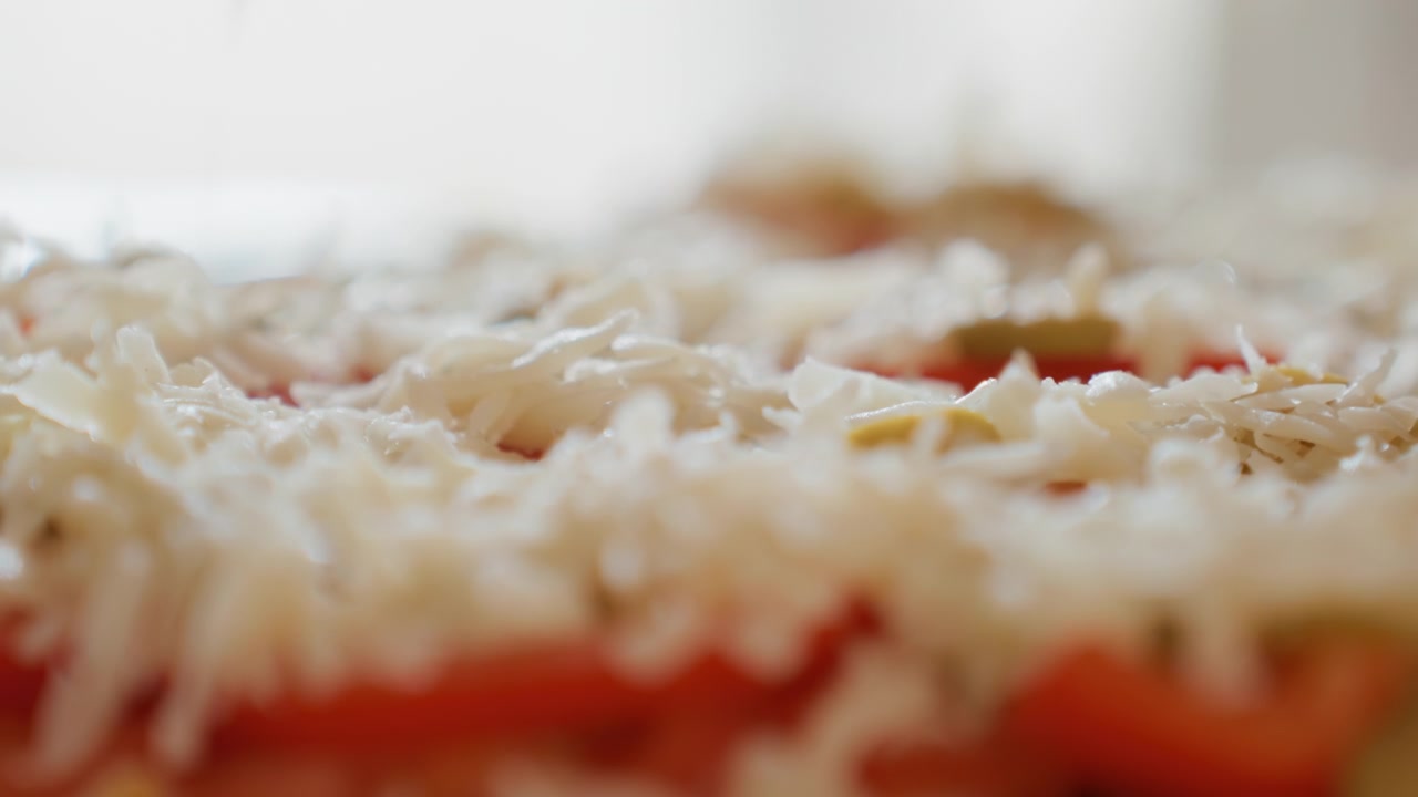 Vista ravvicinata dal basso che mostra formaggio bianco grattugiato che cade su pomodori a fette e ingredienti misti per insalata, creando un condimento a strati con filamenti testurizzati, colori freschi e un dettaglio alimentare appetitoso.