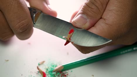 Footage-of-hands-slowly-sharpening-a-pencil-and-some-coloured-pencils-with-a-sharp-knife