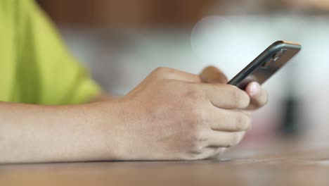 hombre de cerca chequeando el correo electrónico con el teléfono celular en una cafetería