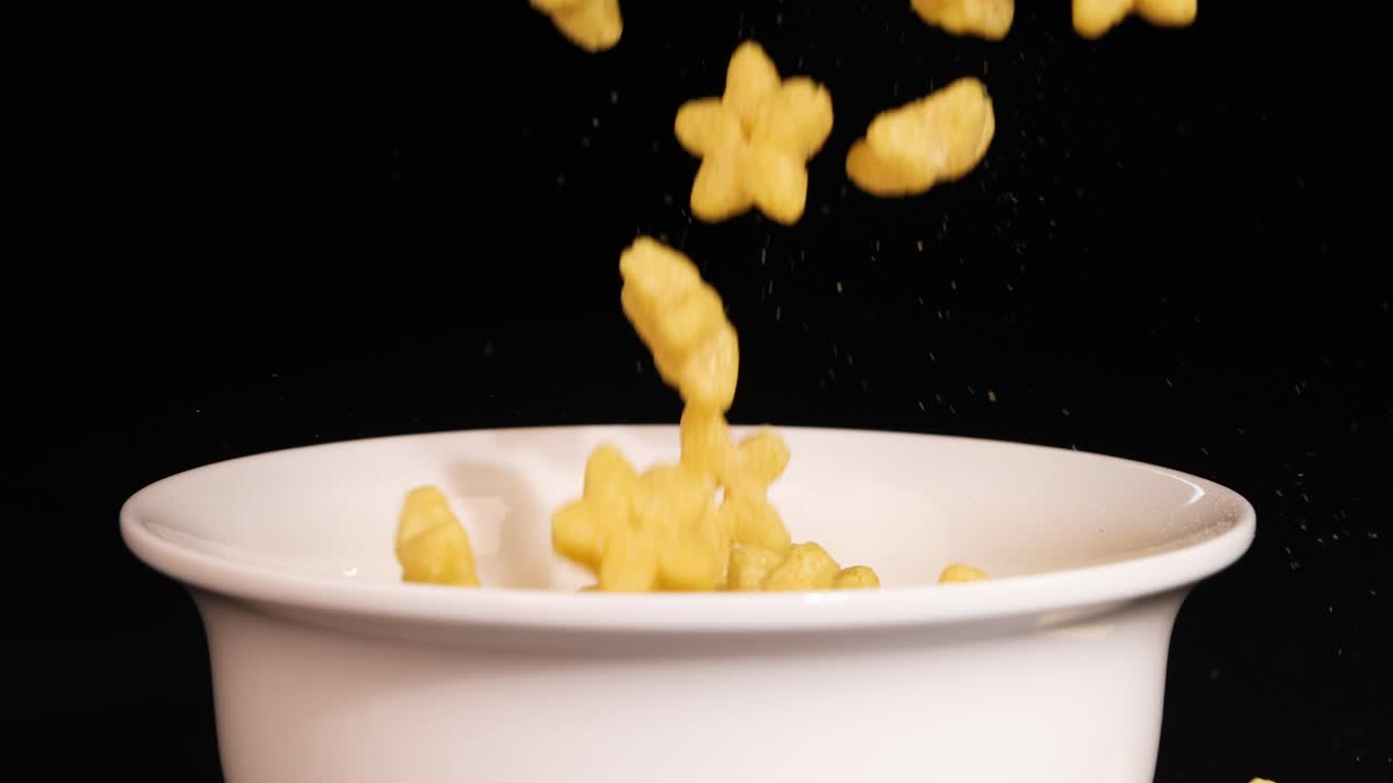 Star-shaped cereal pieces drop into a white bowl against a black background, creating a dynamic and visually appealing scene