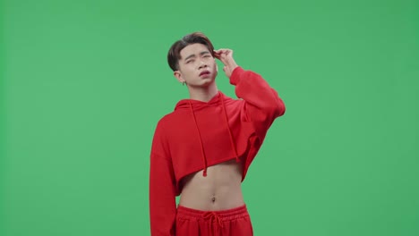 young asian transgender male thinking about something and looking around then raising her index finger and eyes wide open while standing on green screen in the studio