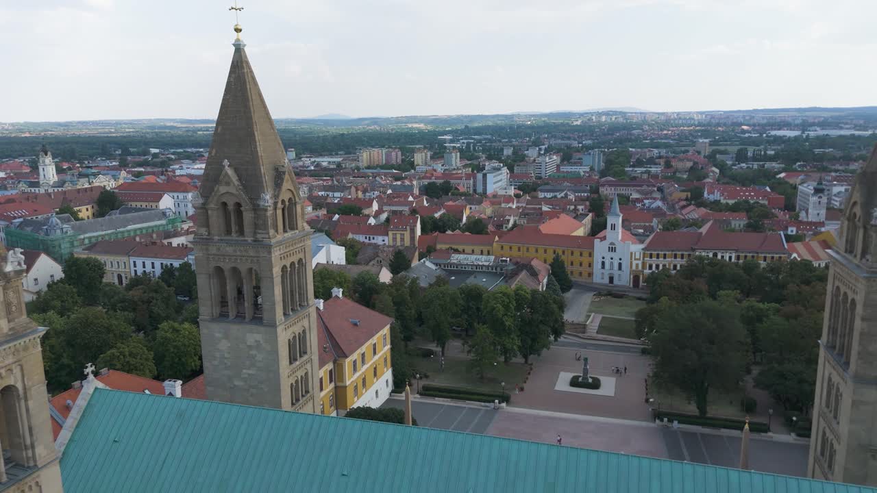 Droneflyvning mellem de to tårne i Pécs Katedral, der viser dens ikoniske arkitektur og byens baggrund