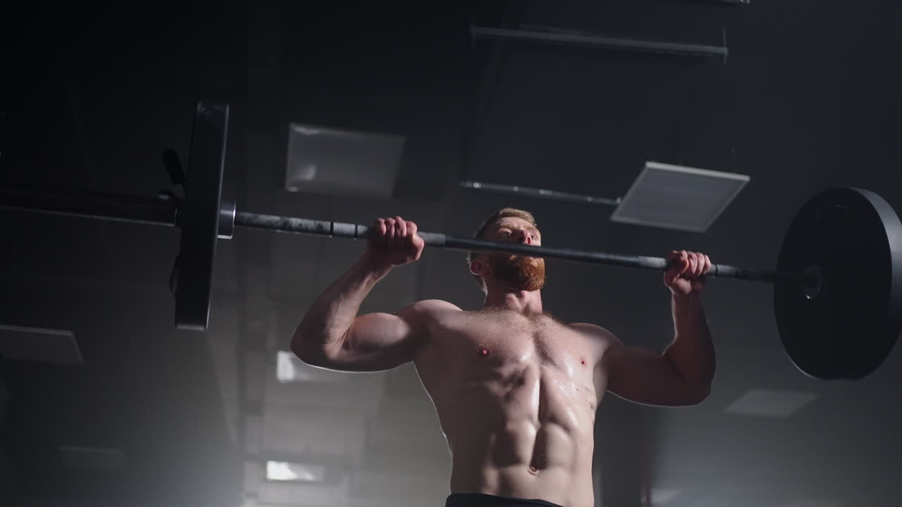 Slow motion of crossfit athlete performs clean and jerk. Young man doing the clean and jerk weightlifting exercise at the gym.