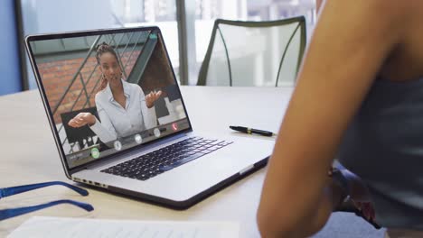 video of african american woman having video call on laptop with african american female coworker