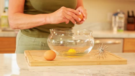 a medium close up of a woman cracking eggs into a bowl in a modern kitchen