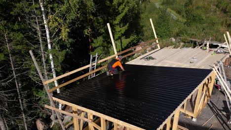 aerial view of a carpenter building a roof in the middle of a forest